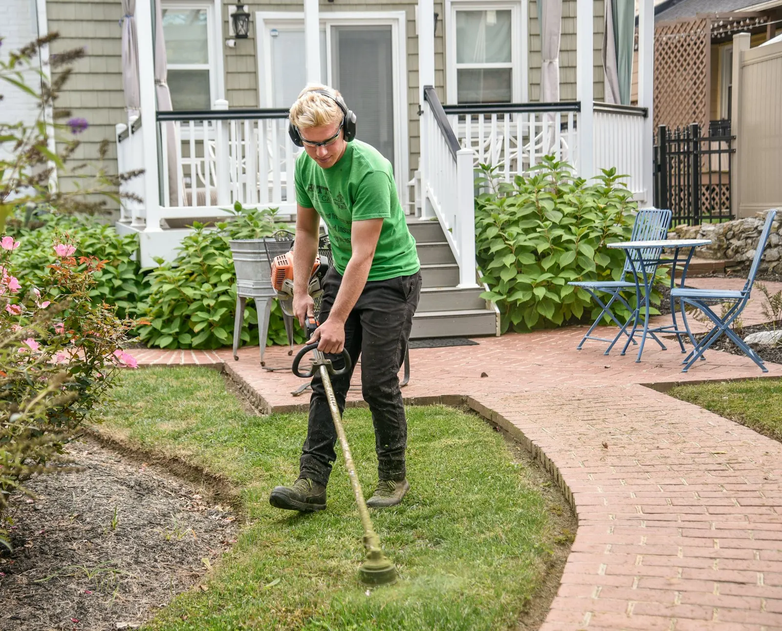 String trimmer cleaning the edge along a residential sidewalk.